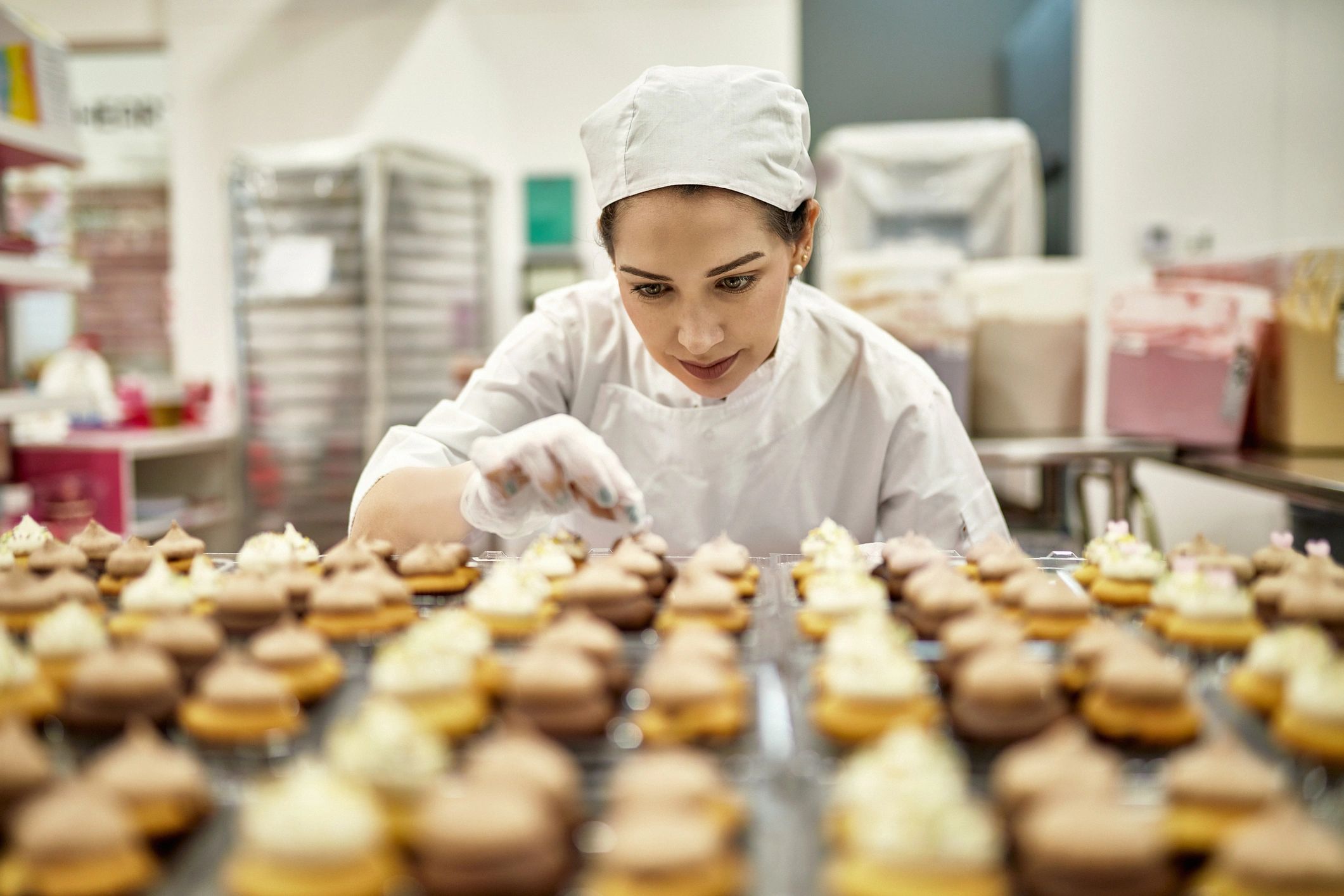 Baker decorating cupcakes in a commercial kitchen