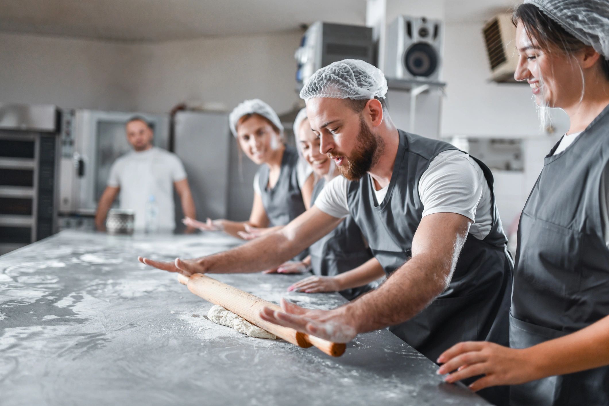 Baker demonstrating dough preparation to apprentices