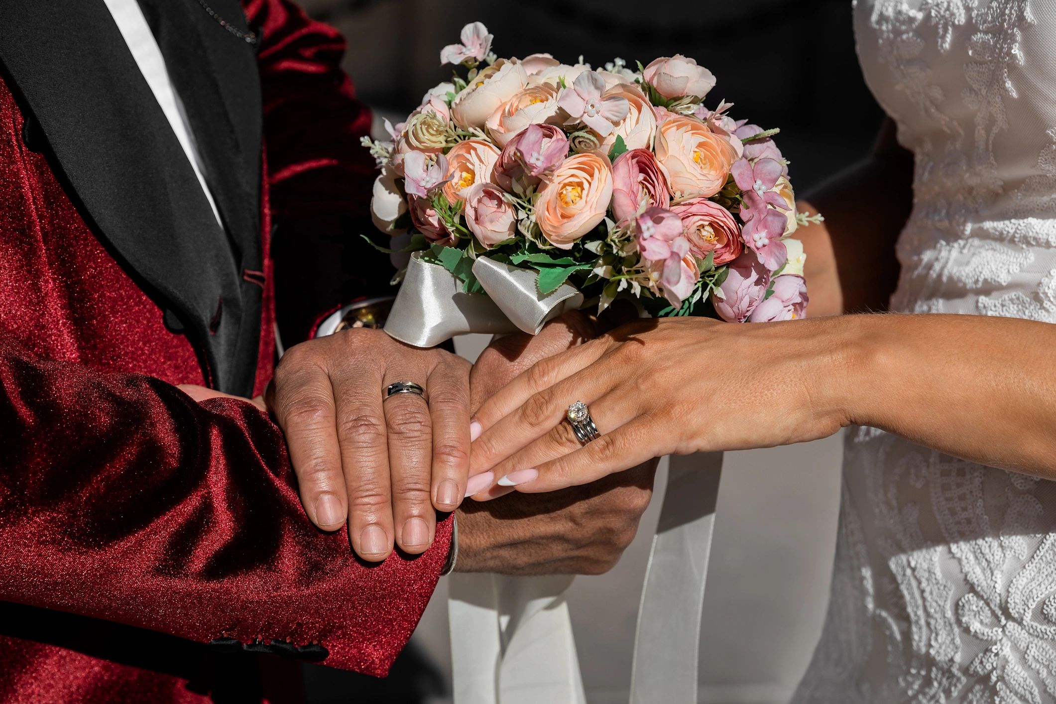 Bride and groom holding hands showing rings