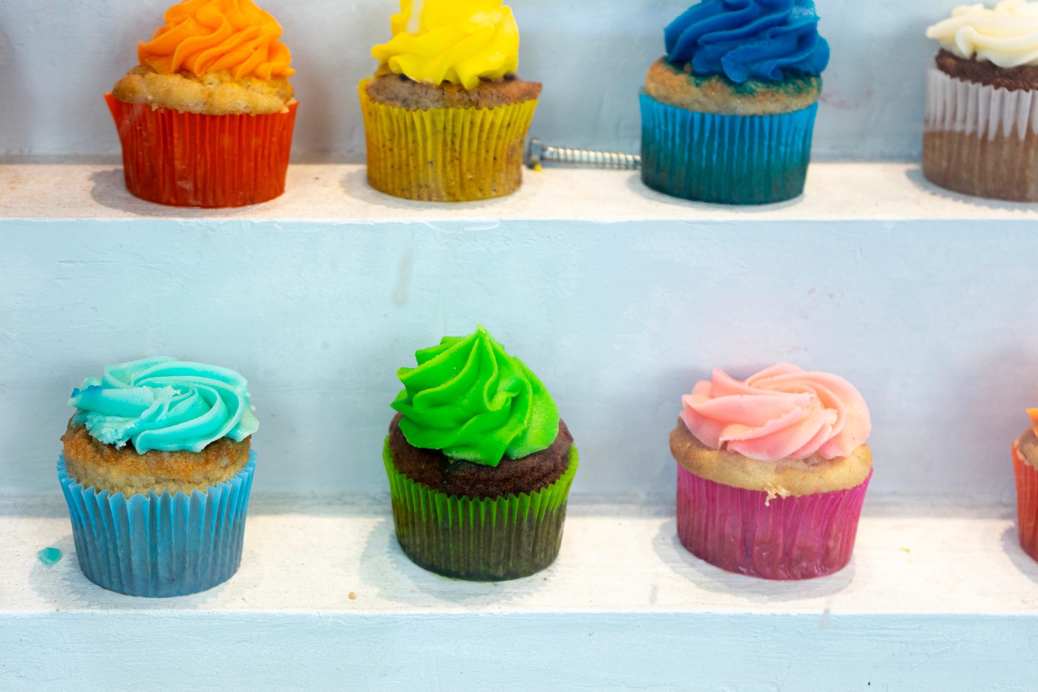 Colorful cupcakes on a shelf in a shop window