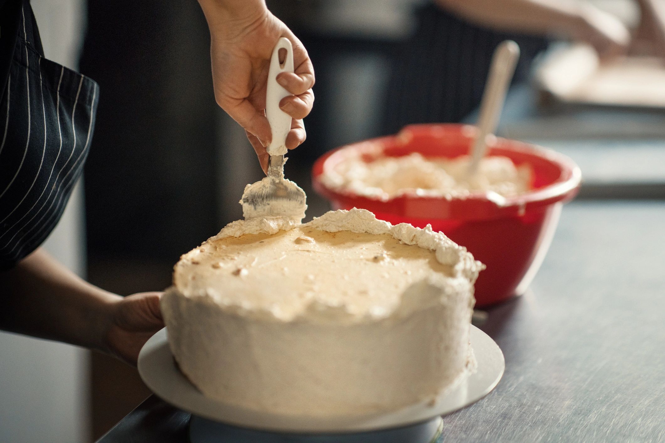 Baker applying icing to a cake in a cake shop