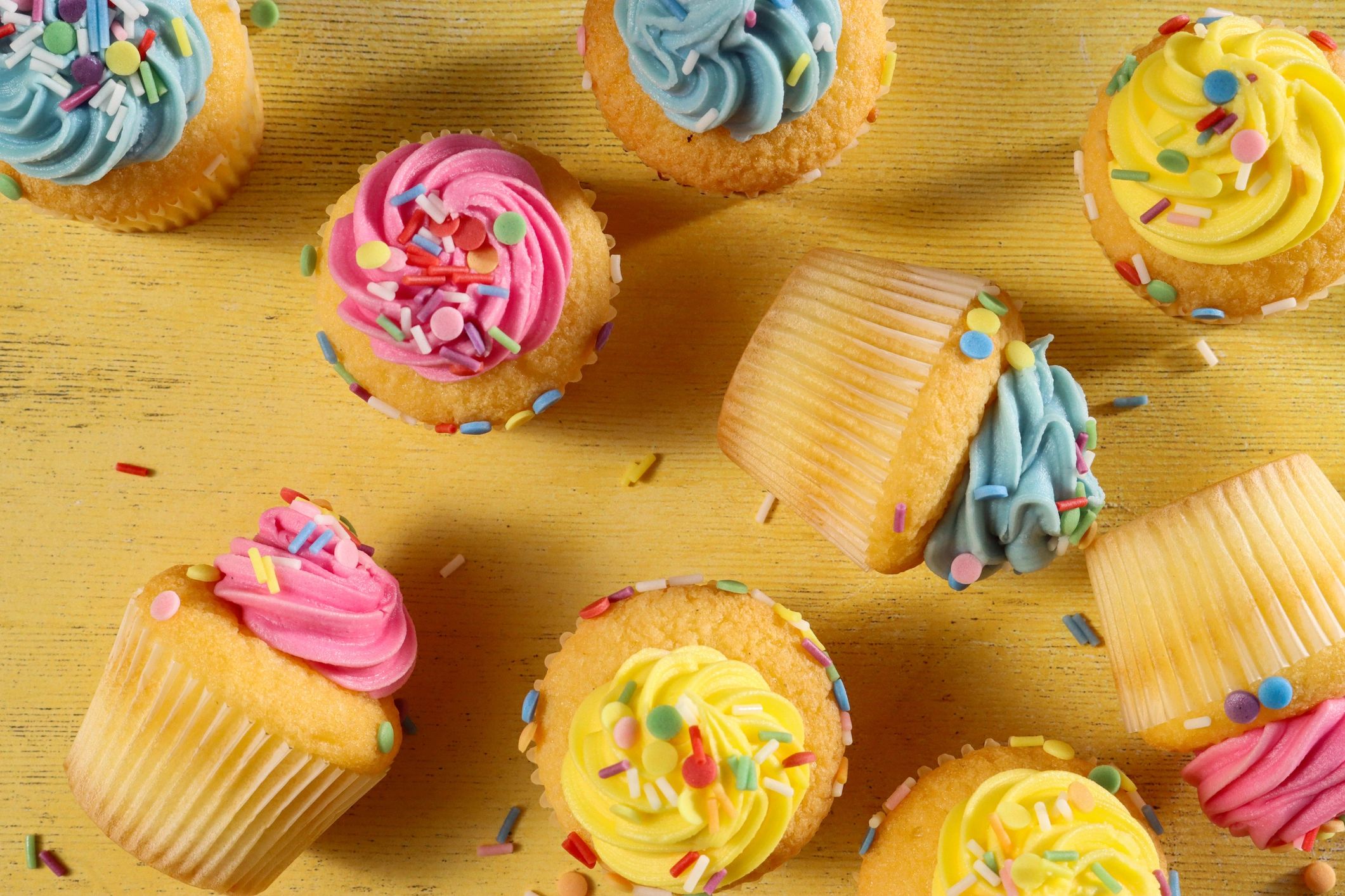 Pastel coloured cupcakes and muffins with butter icing and sprinkles