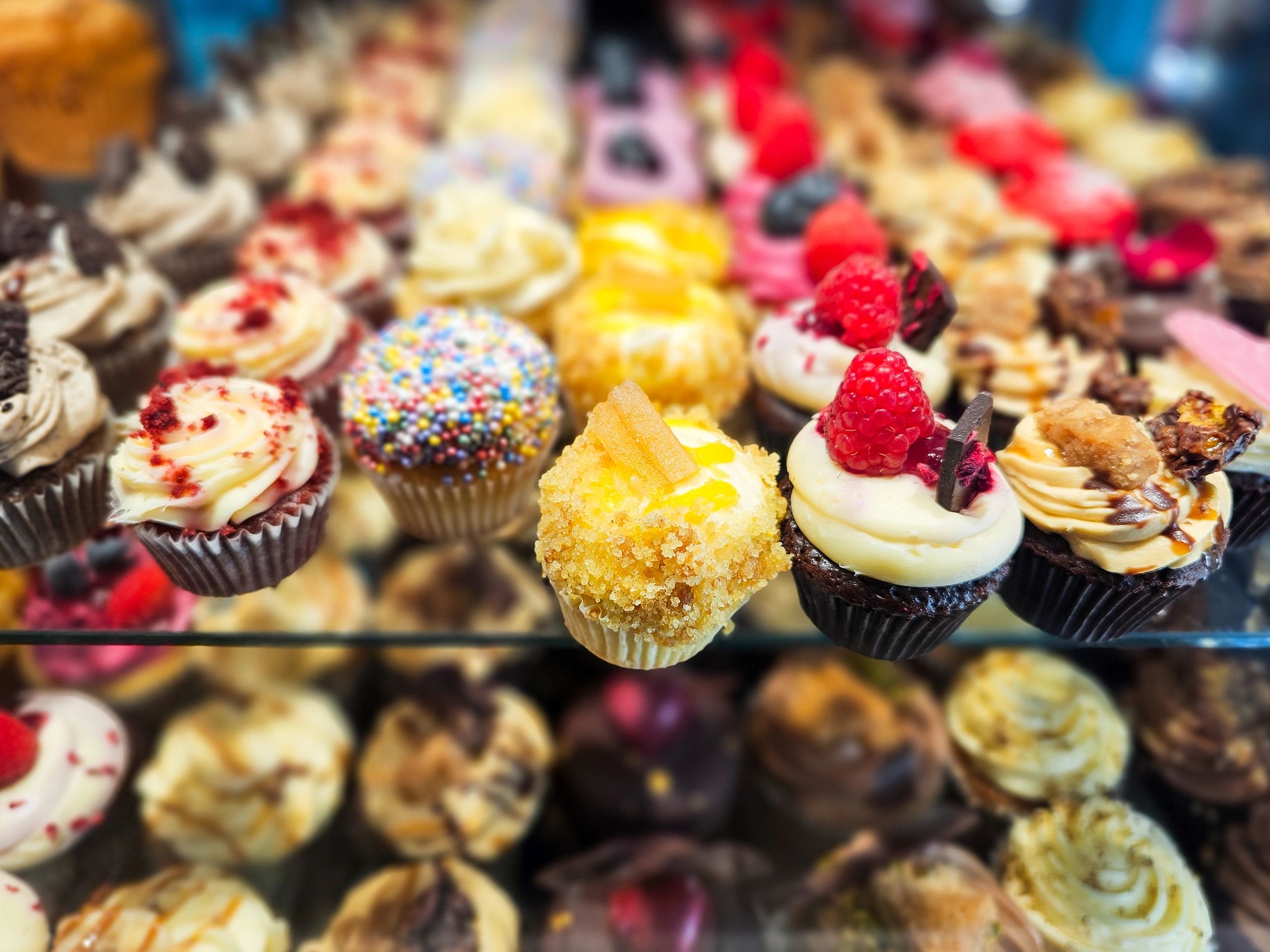 Large selection of cupcakes on display in a bakery window